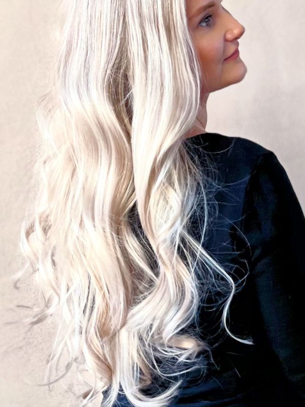 Ylelliset pitkät hiukset muotoiltu pehmeiksi kiharoiksi Niki Newd® Hair Studiossa – ajaton eleganssi, luonnollinen kiilto ja kaunis kokonaisuus.