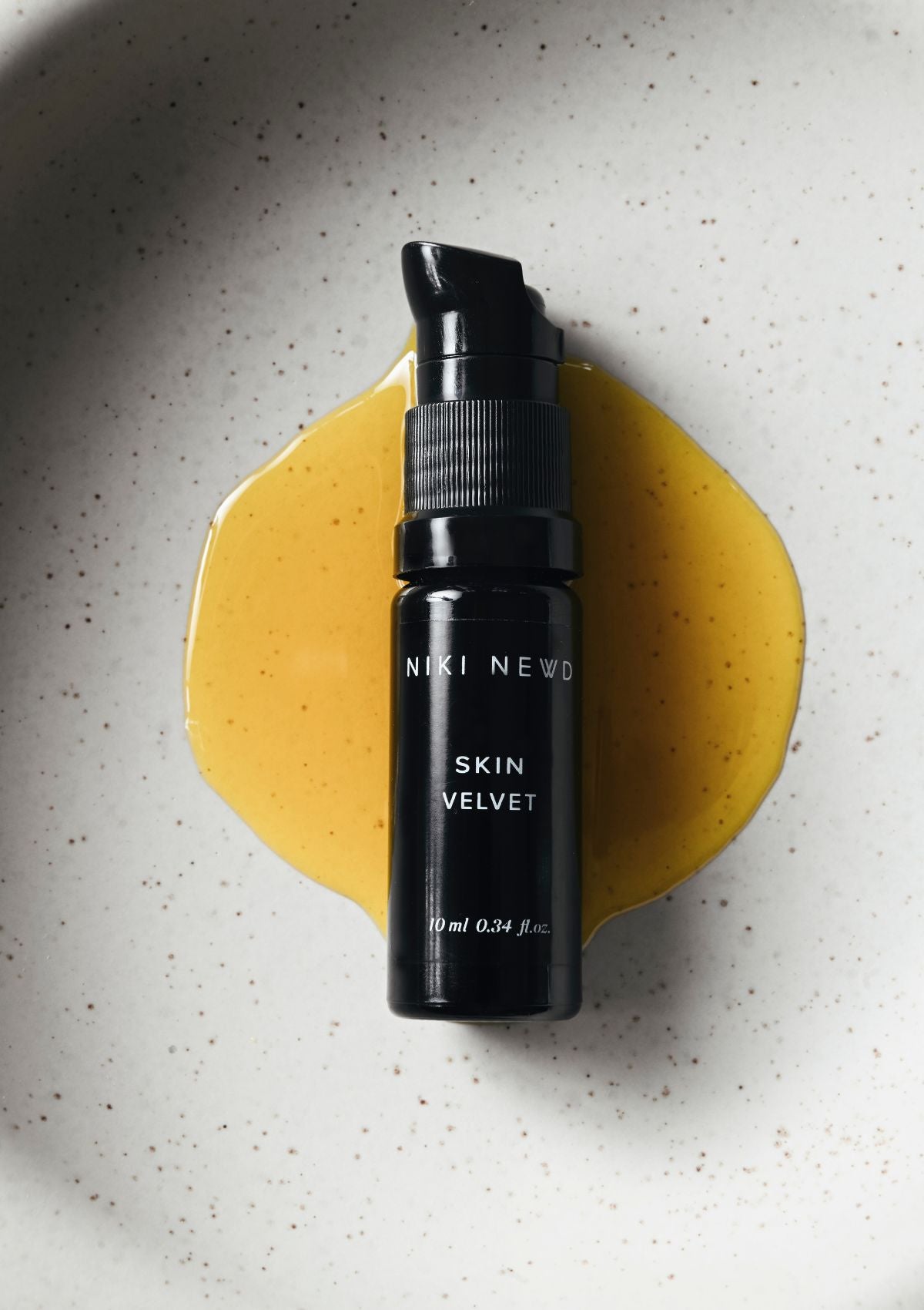 Niki Newd® Skin Velvet serum in a glass pipette – antioxidant oil serum with a rich golden tone that smooths and balances the skin.